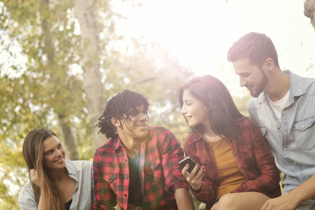 Photo of a midlife woman holding Smartphone with company of friends