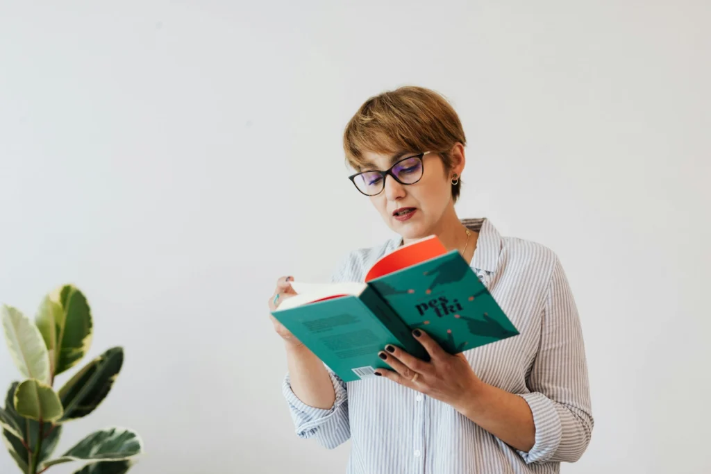 Focused woman reading book with green cover